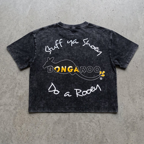 A black acid-wash graphic t-shirt laid flat on a textured gray concrete background. The shirt features white handwritten-style text reading 'Stuff Ya Shoes' and 'Do a Roar' with a central yellow and white 'BONGAROO' logo.